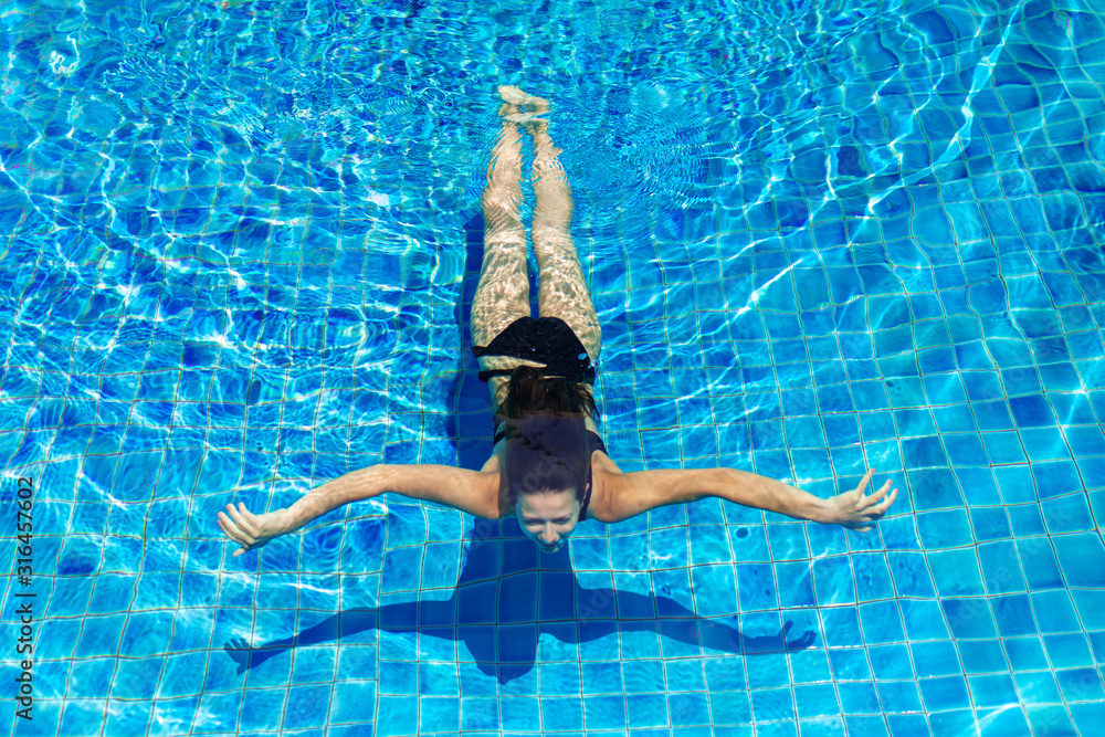 Young sexy slim woman relaxing in swimming pool with crystal blue water