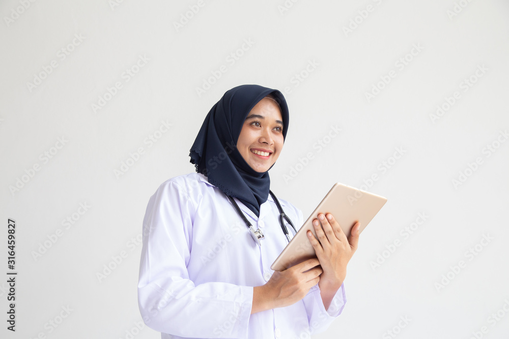 Muslim female medical doctor or nurse in white uniform using tablet computer hospital, concept: Medical technology Electronic medical record for Healthcare, background portrait young Arab hijab Muslim female medical doctor or nurse in white uniform using tablet computer hospital, concept: Medical technology Electronic medical record for Healthcare, background portrait young Arab hijab
