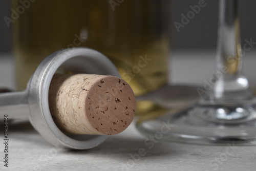 Closeuup of a wine cork in wing style corkscrew with glass and bottle in background. photo