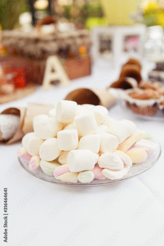 A festive table setting with Beautiful carafe with lemonade and a lot of sweets: muffins, lemonade, marshmallows and cake. Candy bar A festive table setting with Beautiful carafe with lemonade and a lot of sweets: muffins, lemonade, marshmallows and cake. Candy bar