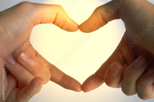 Hands do heart shape or love sign with sun flare for valentine photo