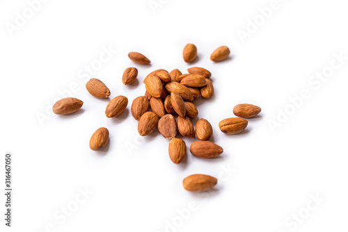 pile of roasted organic almonds with the peel isolated on a white background.