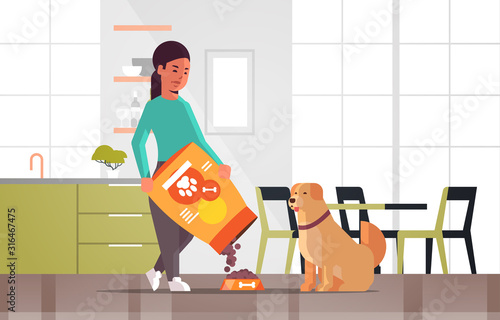 woman feeding hungry labrador retriever girl giving her dog dry food granules domestic life with pet concept modern kitchen interior horizontal full length vector illustration