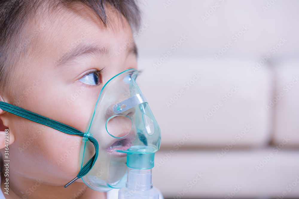 Closeup asian face little children boy using steam inhaler nebulizer mask inhalation Closeup asian face little children boy using steam inhaler nebulizer mask inhalation