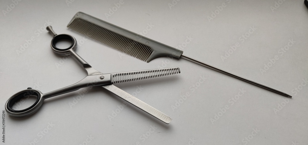 Scissors and comb on a warm white background Scissors and comb on a warm white background