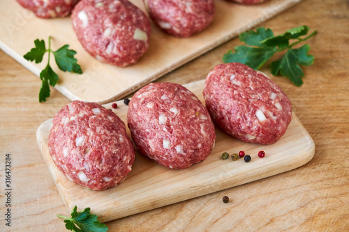 Raw minced meat cutlets on a wooden cutting board