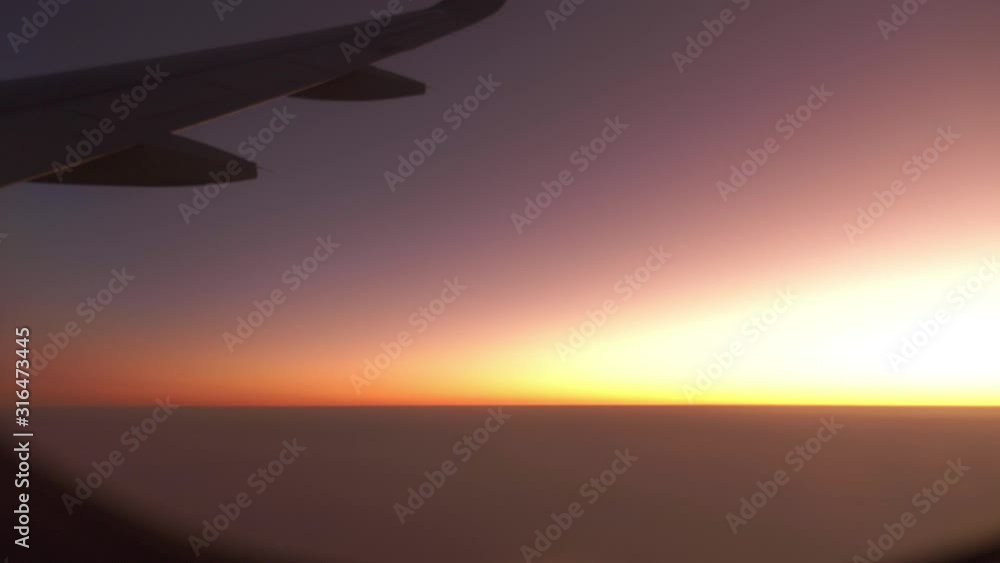 Wing of Airplane Flying Above the Evening Clouds with Sunset Sky. View from the Window of the Plane. Aircraft Flight Above the Clouds Wing of Airplane Flying Above the Evening Clouds with Sunset Sky. View from the Window of the Plane. Aircraft Flight Above the Clouds