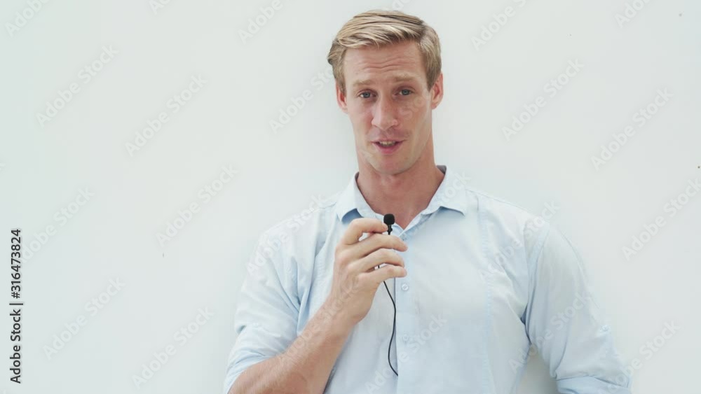 Portrait of young man speaks into microphone, looks at camera and smiles, white background