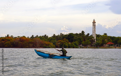 Vászonkép Fisherman on Batticaloa Lagoon with a colonial-era lighthouse in the background