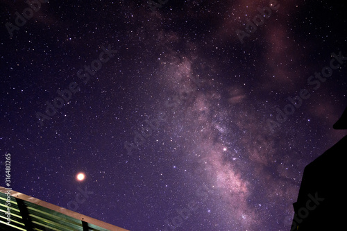 Milky way glaxy and stars with house roof top. Long exposure photograph with grain.