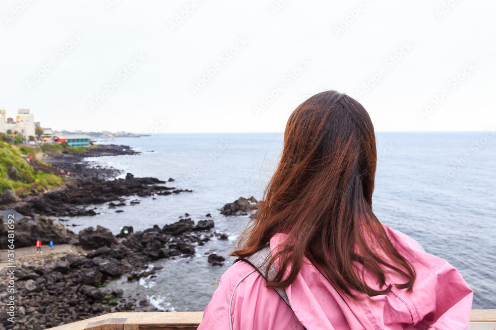 A young lady enjoying the nature scenery at Jeju Yongduam Rock, Jeju Island, South Korea.