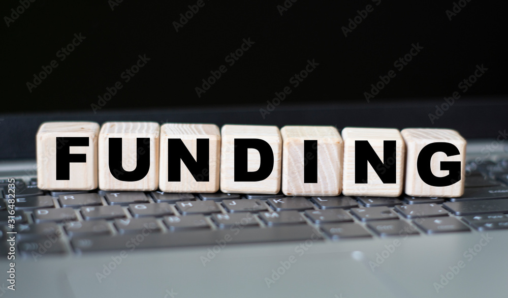 concept word funding on cubes on the background of a laptop concept word funding on cubes on the background of a laptop