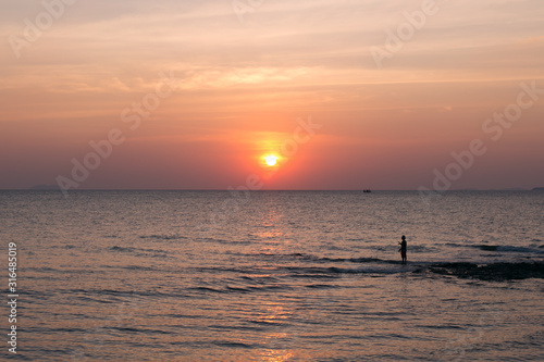 Fisherman on sea pink sunset background. Beautiful color clouds.