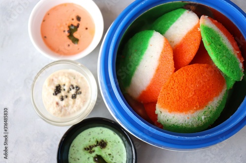 Tiranga Idli or Tricolor Idly cooked in Indian National Flag colors - saffron or orange, white and green. Served with tiranga chutney. Concept for Indian Independence or Republic day greeting card.