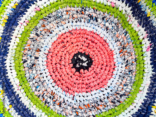 Bright round knitted mat, hand-bound by hook from multicolored pesky strips of fabric