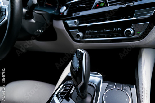 Automatic gear stick of a modern car. Modern car interior details. Close up view. Car detailing. Automatic transmission lever shift. White leather interior with stitching