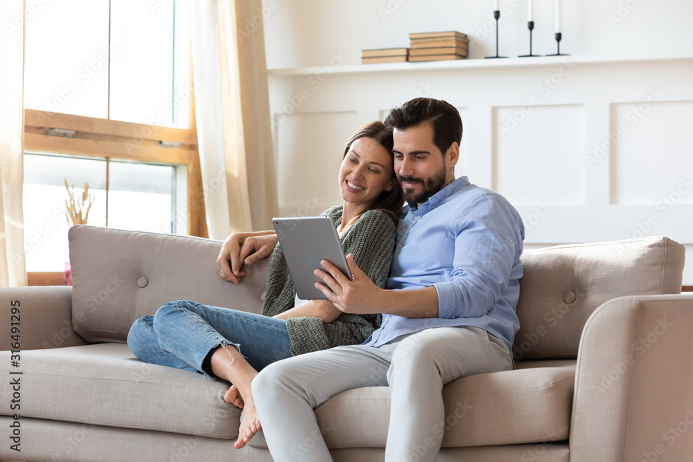 Happy couple relax on couch using tablet together Happy couple relax on couch using tablet together