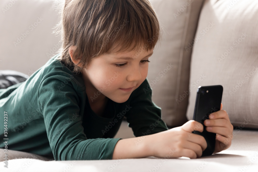 Smart little boy have fun watching video on cellphone gadget Smart little boy have fun watching video on cellphone gadget