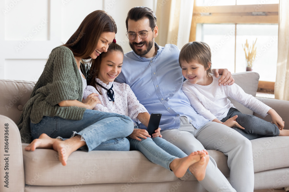 Overjoyed family with kids relax on sofa with smartphone Overjoyed family with kids relax on sofa with smartphone