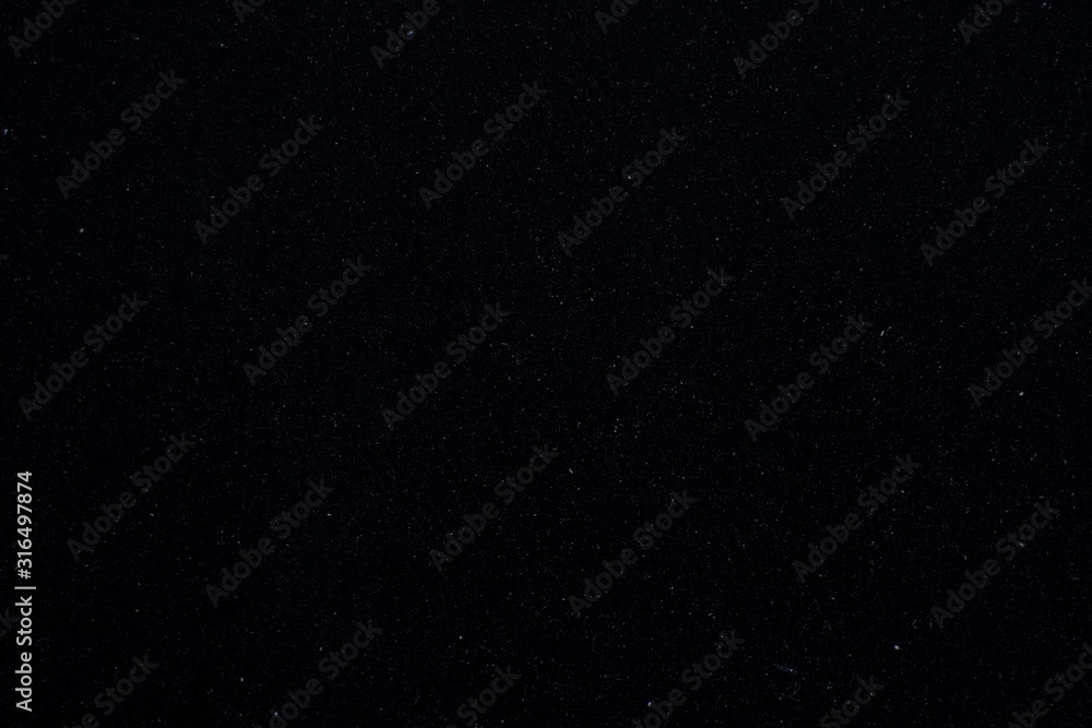 Background texture with a black surface with small specks of white dust Background texture with a black surface with small specks of white dust