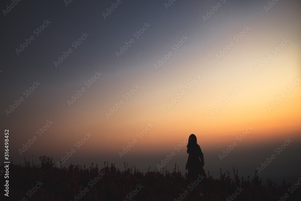 A woman standing among beautiful flower garden on the top of the hill before sunriseSilhouette image of a woman standing among beautiful flower garden on the top of the hill before sunrise A woman standing among beautiful flower garden on the top of the hill before sunriseSilhouette image of a woman standing among beautiful flower garden on the top of the hill before sunrise