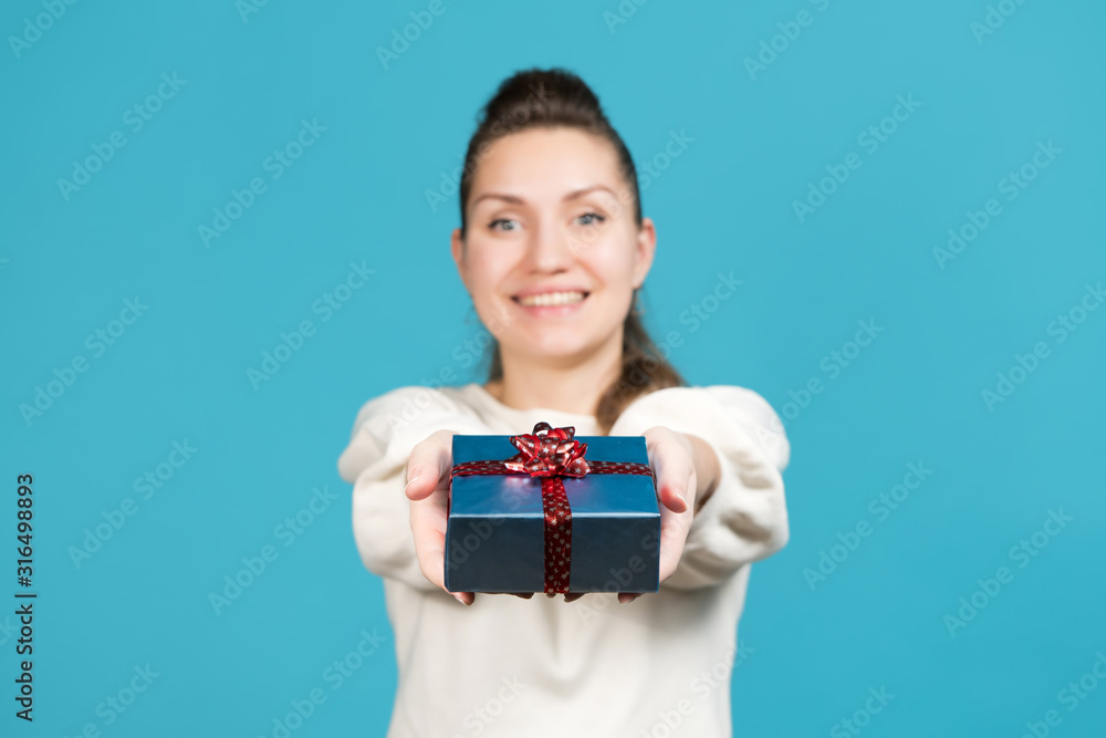 girl holds out a small gift and looks directly at the camera. Selective focus girl holds out a small gift and looks directly at the camera. Selective focus