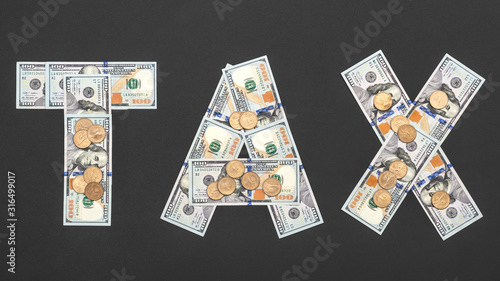 Word "tax" written by dollar bills and coins on black.