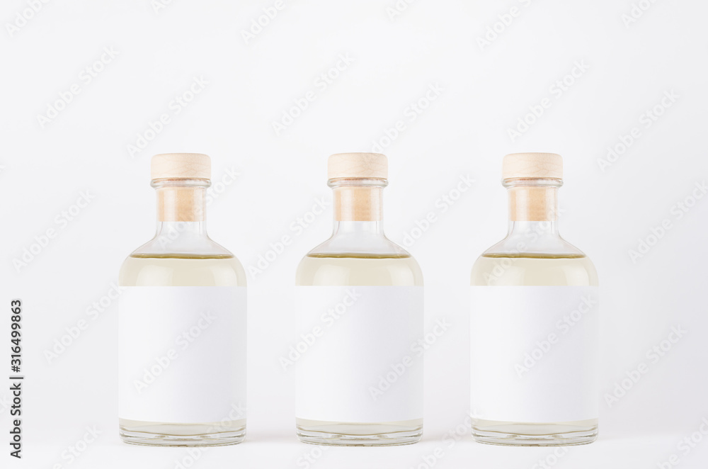 Three glass bottles for cosmetic, perfume, alcohol drink with white label, cork, yellow liquid on white background, mock up for design. Three glass bottles for cosmetic, perfume, alcohol drink with white label, cork, yellow liquid on white background, mock up for design.