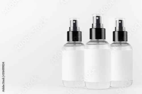 Transparent spray bottles for cosmetics product with white blank label on white background, mock up for branding, advertising, presentation, design.