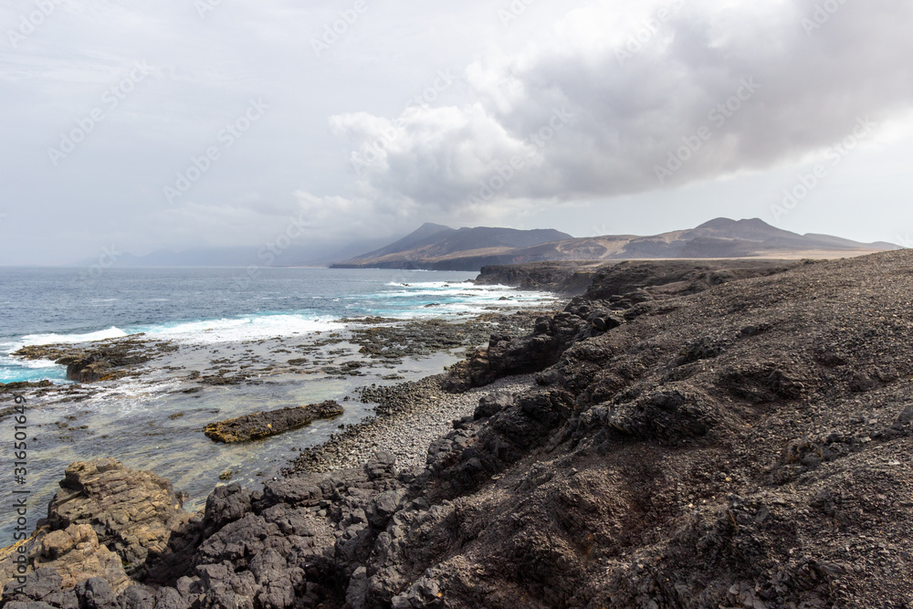 Panoramic view at the coastline in the natural park of Jandia (Parque Natural De Jandina) on canary island Fuerteventura with gravel and lava rocks