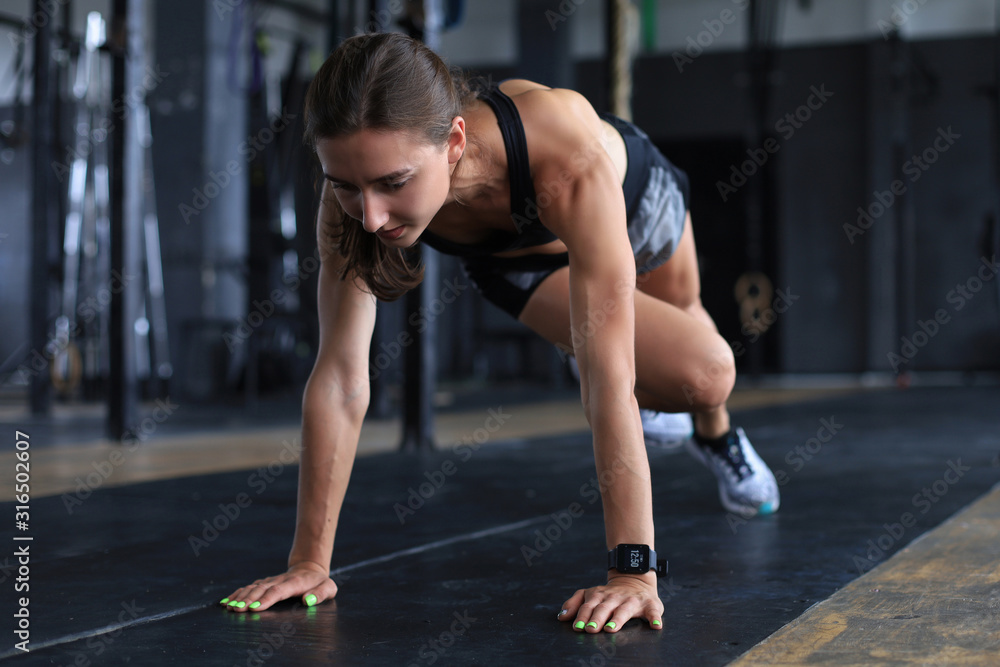 Portrait of a muscular woman doing planks on gym floor. Portrait of a muscular woman doing planks on gym floor.