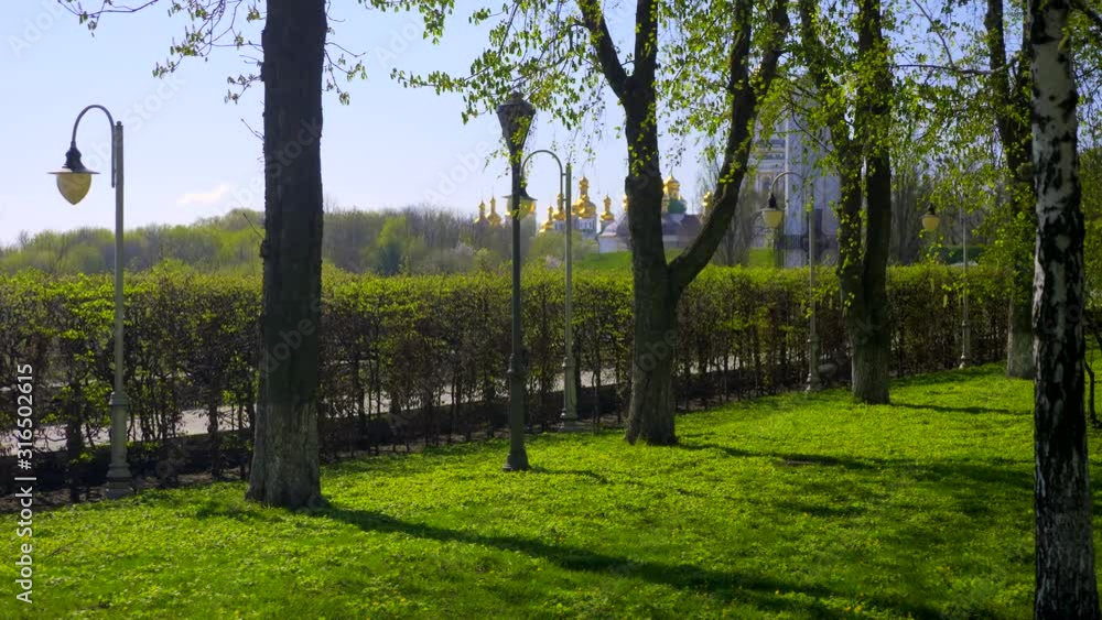 Camera Moving On Path In City Park. Monastery Church Cathedral Buildings Obelisk Monument. Sunny Day Blue Sky. Kyiv Pechersk Lavra. Kyiv Ukraine Camera Moving On Path In City Park. Monastery Church Cathedral Buildings Obelisk Monument. Sunny Day Blue Sky. Kyiv Pechersk Lavra. Kyiv Ukraine