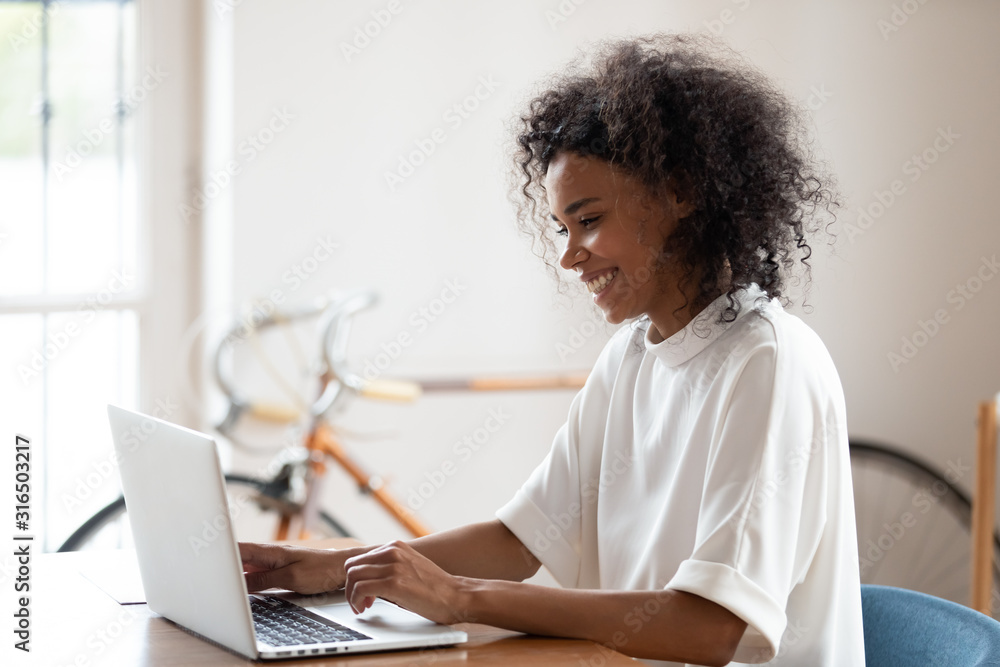 Smiling confident African American businesswoman using laptop in office Smiling confident African American businesswoman using laptop in office