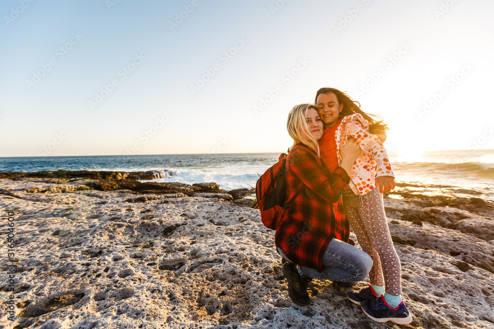 A little girl and mom walk near the sea, they play and hug