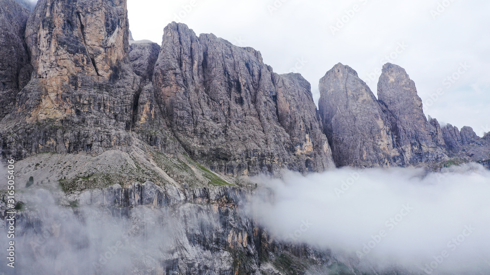 Aerial view of Dolomites Alpine mountains in fog and low clouds. South Tyrol, Italy.