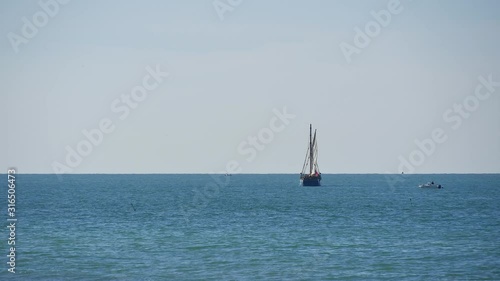 Small wooden schooner sailing near the coast photo