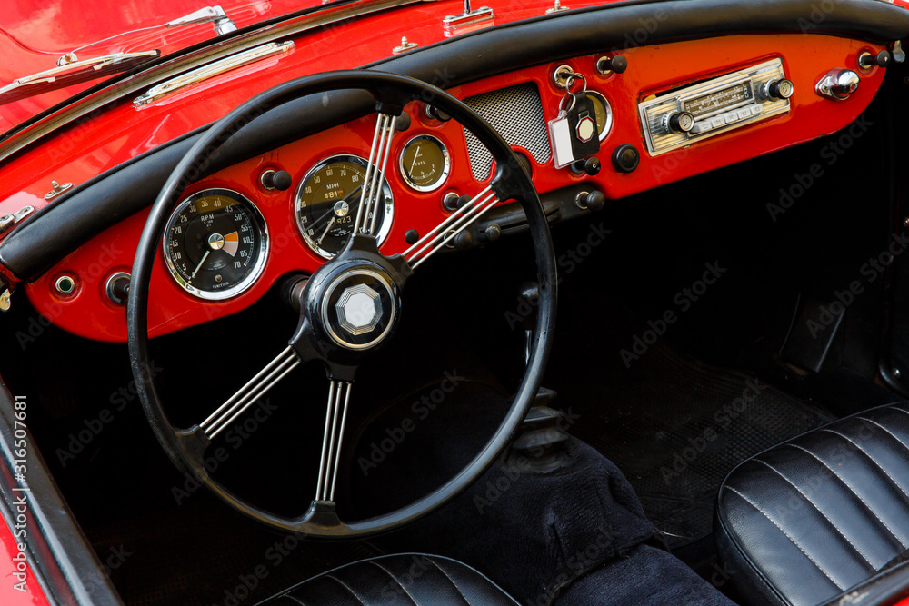 Elegant retro car, vintage cabriolet and red dashboard close-up, behind the big black wheel of such a classy automobile you want to press the gas and go on a sunny summer day in South of France