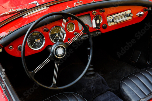 Elegant retro car, vintage cabriolet and red dashboard close-up, behind the big black wheel of such a classy automobile you want to press the gas and go on a sunny summer day in South of France © Konstantin Koreshkov