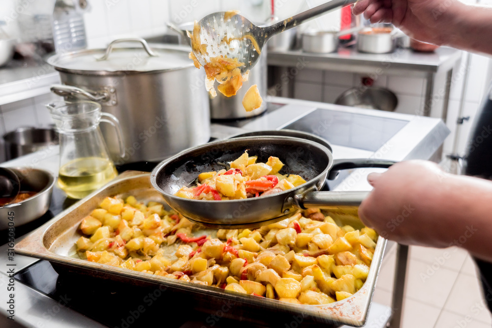 Chef cooks fried potatoes with pieces of meat in a restaurant kitchen Chef cooks fried potatoes with pieces of meat in a restaurant kitchen