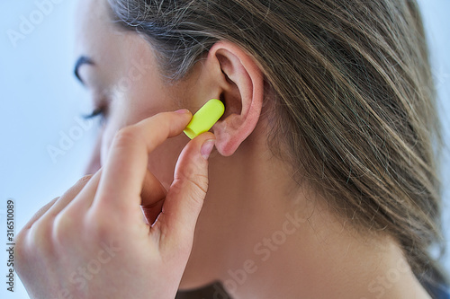 Foto Young brunette woman using earplugs for noise protection at home