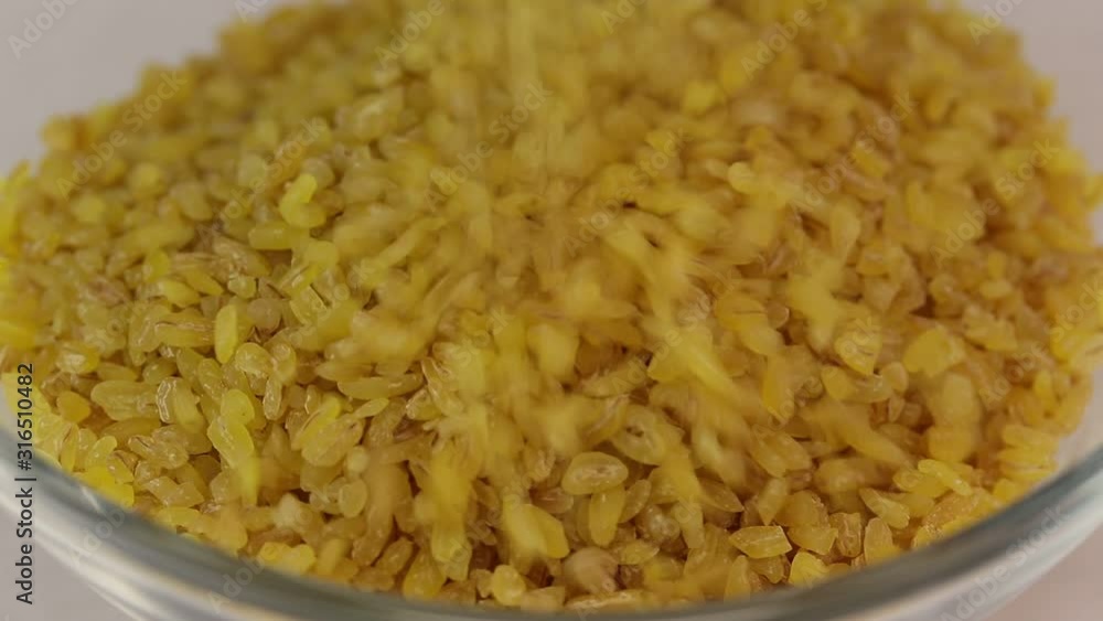 Krupa bulgur falls into a glass transparent bowl, close-up Krupa bulgur falls into a glass transparent bowl, close-up