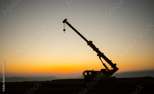 Abstract Industrial background with construction crane silhouette over amazing sunset sky. Tower crane against the evening sky. Industrial skyline. Selective focus photo