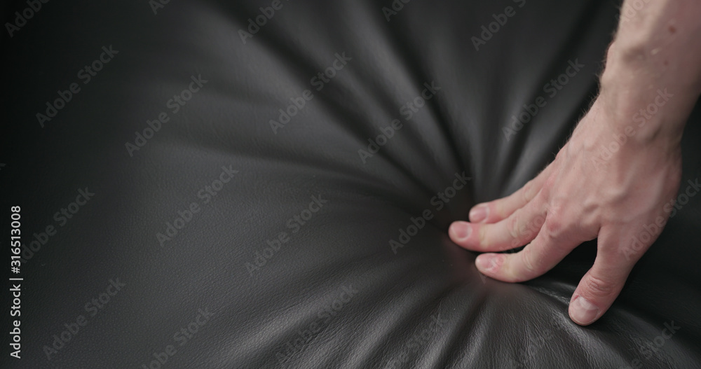 man hand checking dark brown leather cushion closeup