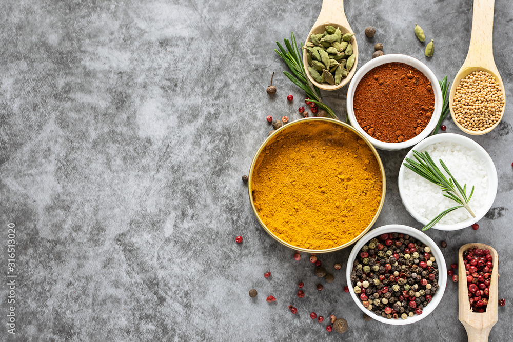 Assortment of spices and herbs on grey concrete background with copy space for your design.