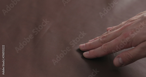 man shows brown leather piece closeup