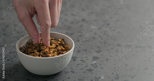 man hand take dried seaberry from white bowl on terrazzo countertop