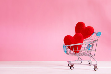 The red Heart shapes  in shopping cart on sweet pink background , the love concept for shopping on valentines day with sweet and romantic moment