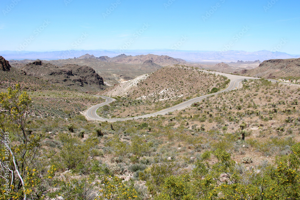 Curved narrow road and a dry rocky hill in Oatman, Arizona - Historic Route 66 - mountains on the horizon. Stock photo