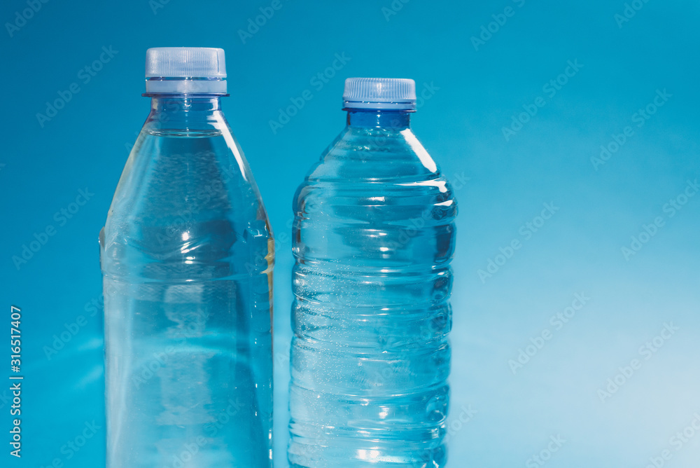 Two different plastic bottles with a sparkle of water on a blue background. Copyspace, place for text Two different plastic bottles with a sparkle of water on a blue background. Copyspace, place for text