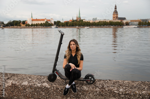 Fit Woman by electric scooter with a river city background - Shot of Modern transportation gadget and popular futuristic device among young people - Eastern European Latvia Riga © dissx
